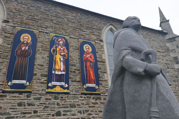 Zusätzlich zur 1989 aufgestellten Kiliansstatue waren für die besonderen Tage außen vor der Kirche von Mullagh Fahnen der drei Frankenapostel aufgehängt. Zusätzlich zur 1989 aufgestellten Kiliansstatue waren für die besonderen Tage außen vor der Kirche von Mullagh Fahnen der drei Frankenapostel aufgehängt.