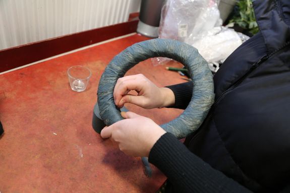 Vor dem Binden wird der Strohkranz mit dem Wickelband umkleidet. Dieses wird im Anschluss mit Nadeln festgesteckt.