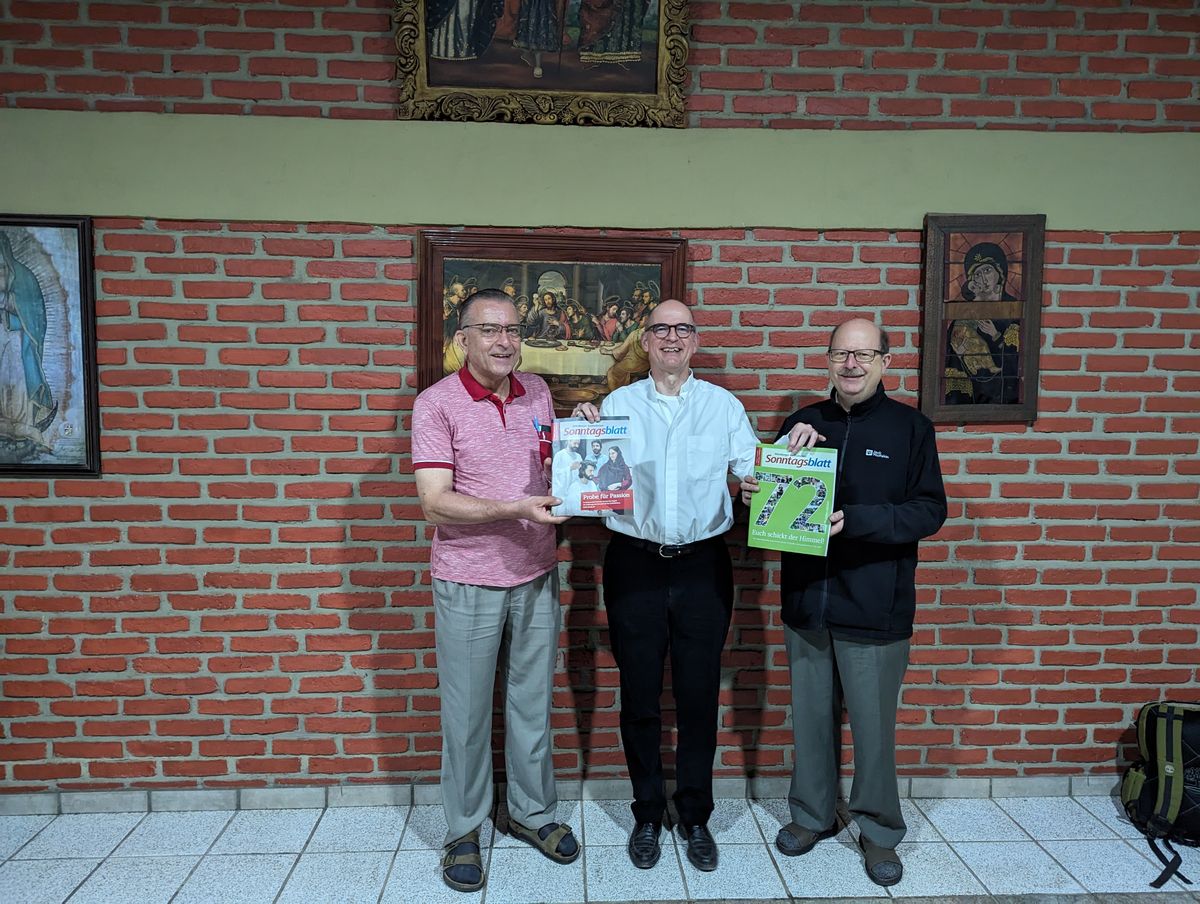 Bischof Dr. Franz Jung (Mitte) überreicht den Missionaren Thomas Hermes (links) und Christian Müssig jeweils ein Exemplar des Würzburger katholischen Sonntagsblatts.