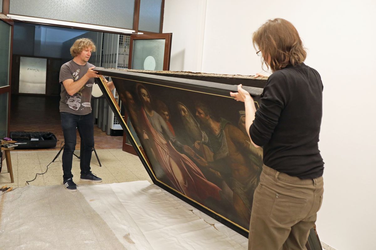 Vorsichtig lösen Christoph Deuter, wissenschaftlicher Mitarbeiter des Kunstreferats, und Restauratorin Gudrun Hanika das Gemälde vom Rahmen.
