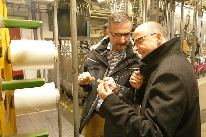 Thomas Rasch, Betriebsleiter der Firma PHP Fiber (links), erklärt Bischof Dr. Franz Jung die Herstellung und Funktion von Technischem Garn.