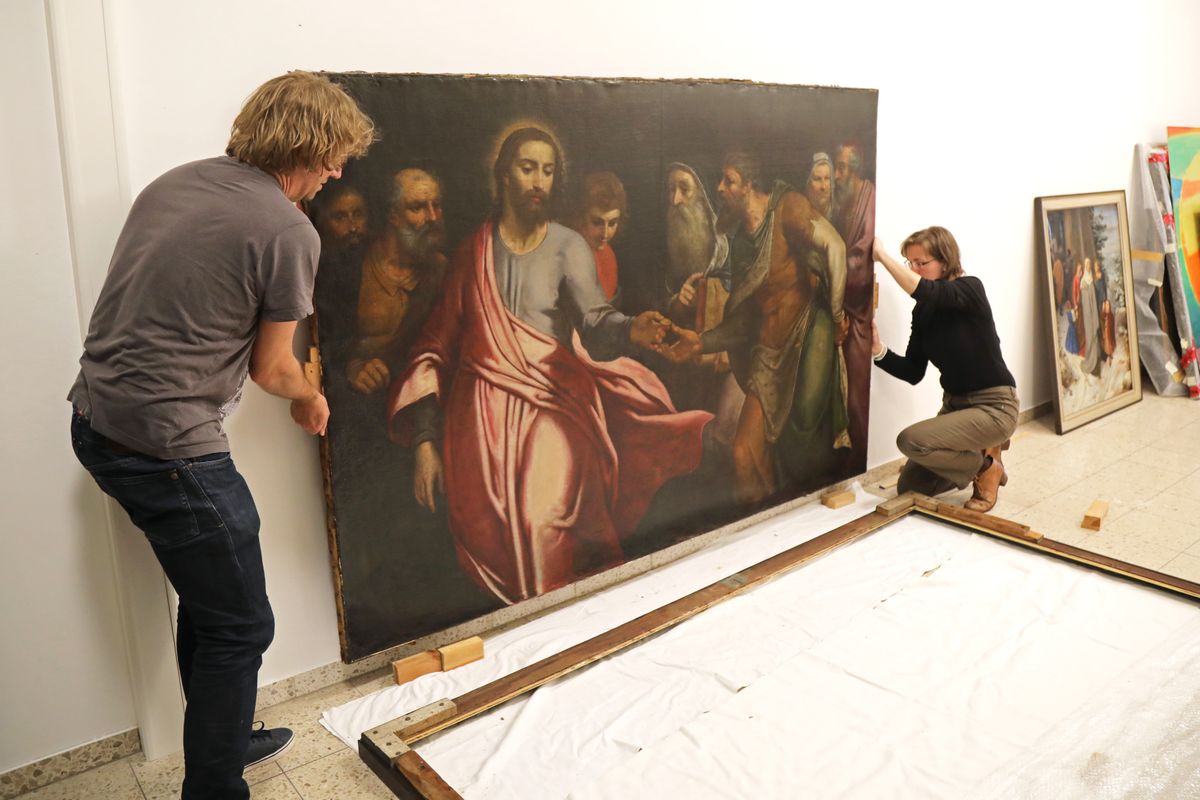 Geschafft - der Rahmen ist gelöst. Christoph Deuter, wissenschaftlicher Mitarbeiter des Kunstreferats, und Restauratorin Gudrun Hanika sichern das Gemälde. 