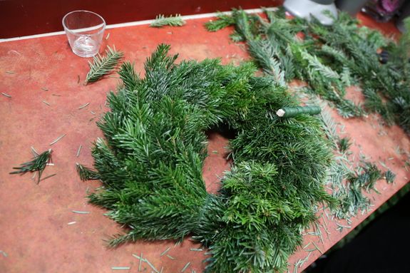 Zum Befestigen des fertigen Adventskranzes wird der Draht versteckt und gekürzt. Dazu wird eine Schlaufe aus dem Draht geformt. Diese wird mehrmals eingedreht. Damit keine Verletzungsgefahr entsteht, wird das Ende des Drahtes in den Strohkranz gesteckt. 