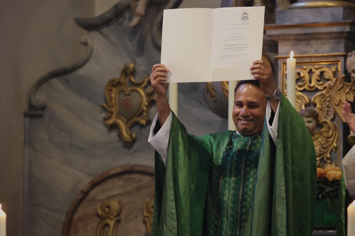 Pater Nelson Antoney präsentiert den Gläubigen seine Ernennungsurkunde.