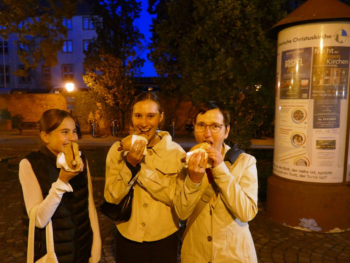 Drei Besucherinnen der Nacht der offenen Kirchen lassen sich die ökumenische Bratwürste schmecken.  Drei Besucherinnen der Nacht der offenen Kirchen lassen sich die ökumenische Bratwürste schmecken.