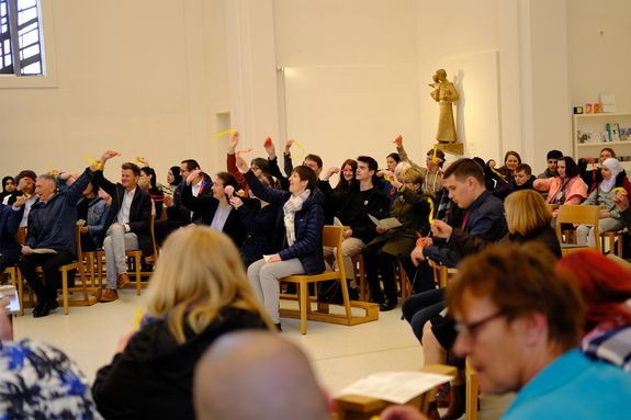 Mit Krepppapier in Feuerfarben erinnerten die Teilnehmerinnen und Teilnehmer im Gottesdienst an das Pfingstereignis.