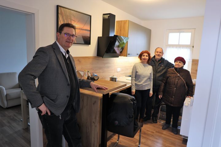 Dekan Dr. Andreas Krefft (links) mit den ukrainischen Geflüchteten  (von links) Svetlana und Oleksander Pavlichuck und Maria Builenkova in der ehemaligen Kaplanswohnung von Mariä Himmelfahrt in Bad Neustadt.