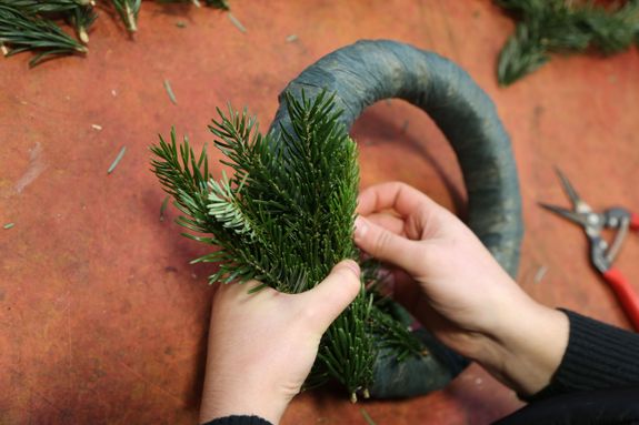 Die Tannenzweige werden in unterschiedliche Längen geschnitten. Es sollten kleine, mittlere und große Zweige abgeschnitten und zurechtgelegt werden. Dabei werden die Stiele entfernt, damit der Kranz nicht zu dick wird. Am besten werden möglichst dünne Zweige verwendet. 