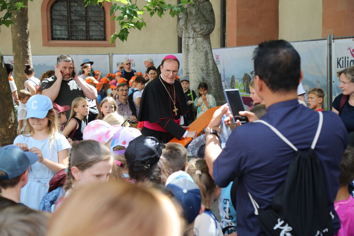 Mit rund 1300 Kommunionkindern und ihren Begleitern hat Weihbischof Paul Reder am Montag, 8. Juli, einen Gottesdienst im Kiliansdom gefeiert. Weil einige Kinder auf den Gruppenfotos schlecht zu sehen waren, trug der Weihbischof kurzerhand eine Bank herbei.  