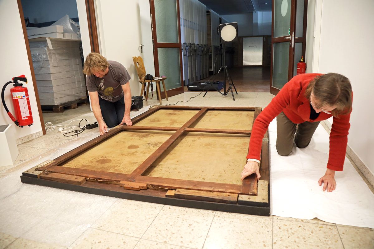 Zunächst müssen Restauratorin Gudrun Hanika und Christoph Deuter, wissenschaftlicher Mitarbeiter des Kunstreferats, das Bild aus dem Rahmen lösen.