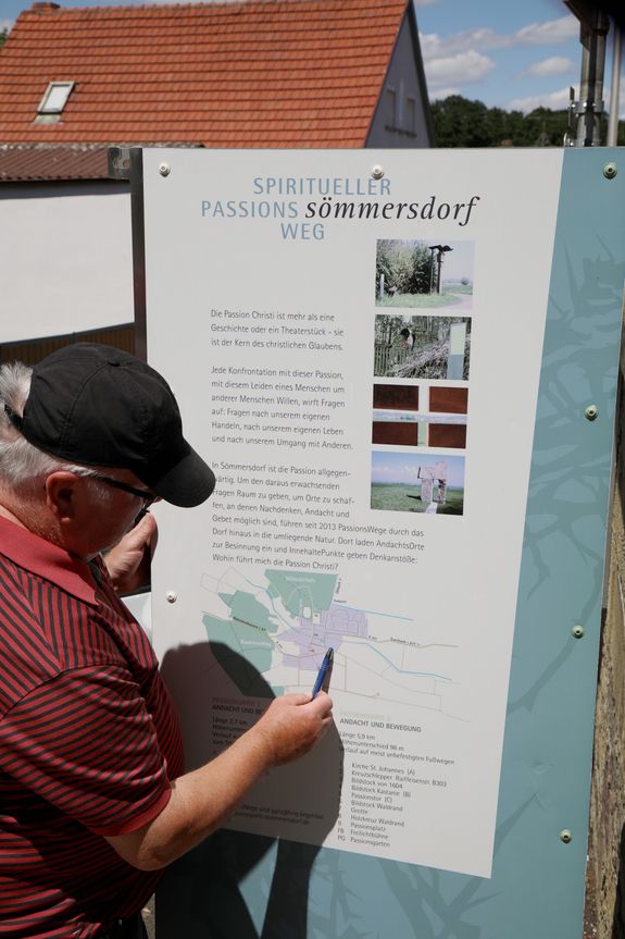 Hubert Rüth erläutert anhand der Karte an der Kirche den Verlauf der beiden Wege.