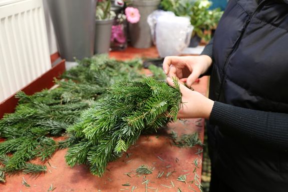 Zum Ende hin sollten die Tannenzweige unter die Zweige vom Anfang geklemmt werden, sodass möglichst alle Lücken geschlossen werden. Sollten trotzdem Lücken entstehen, können diese am Ende noch mit Tannengrün gefüllt werden. 